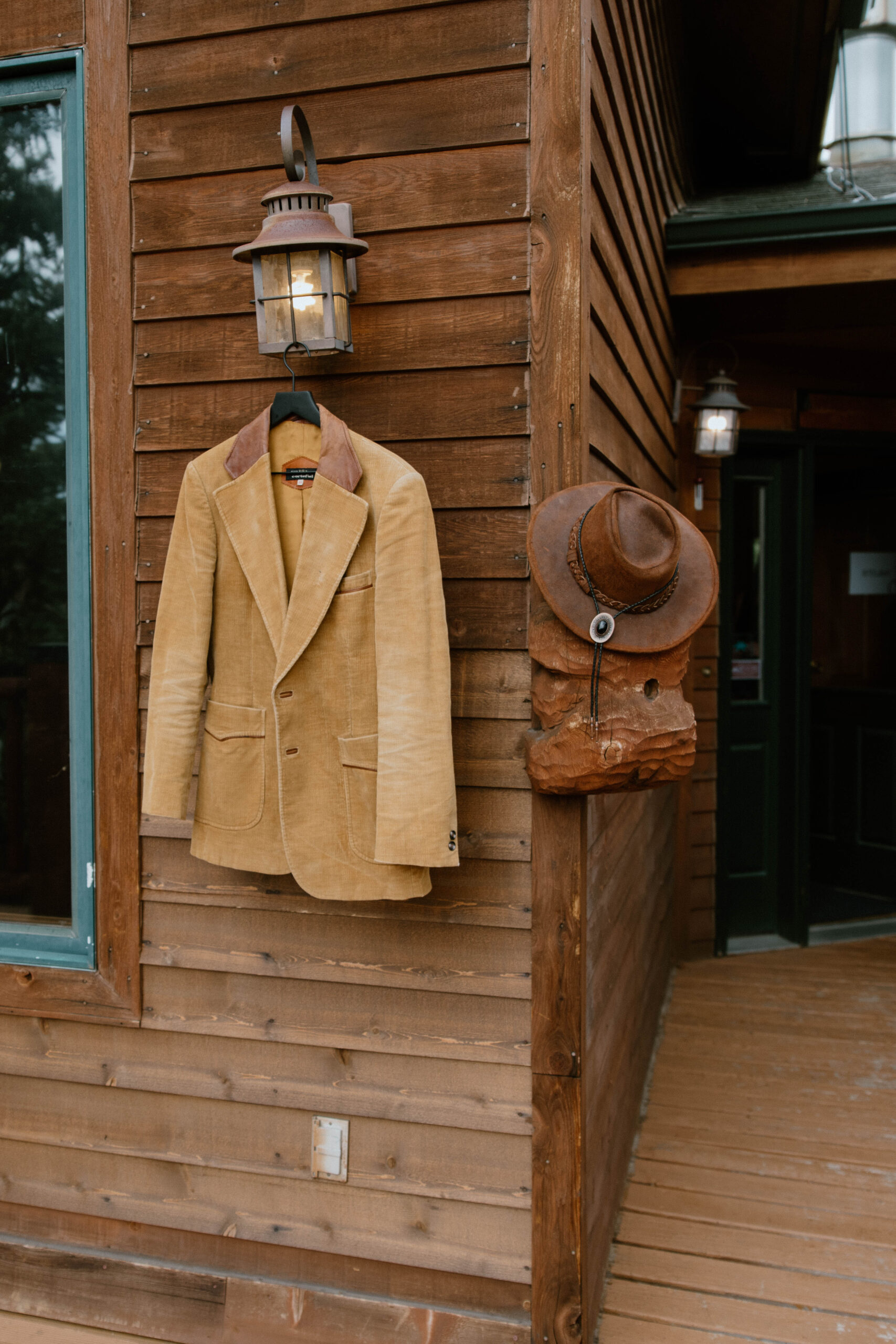 A wedding suit jacket hangs with a hat outside a cabin door