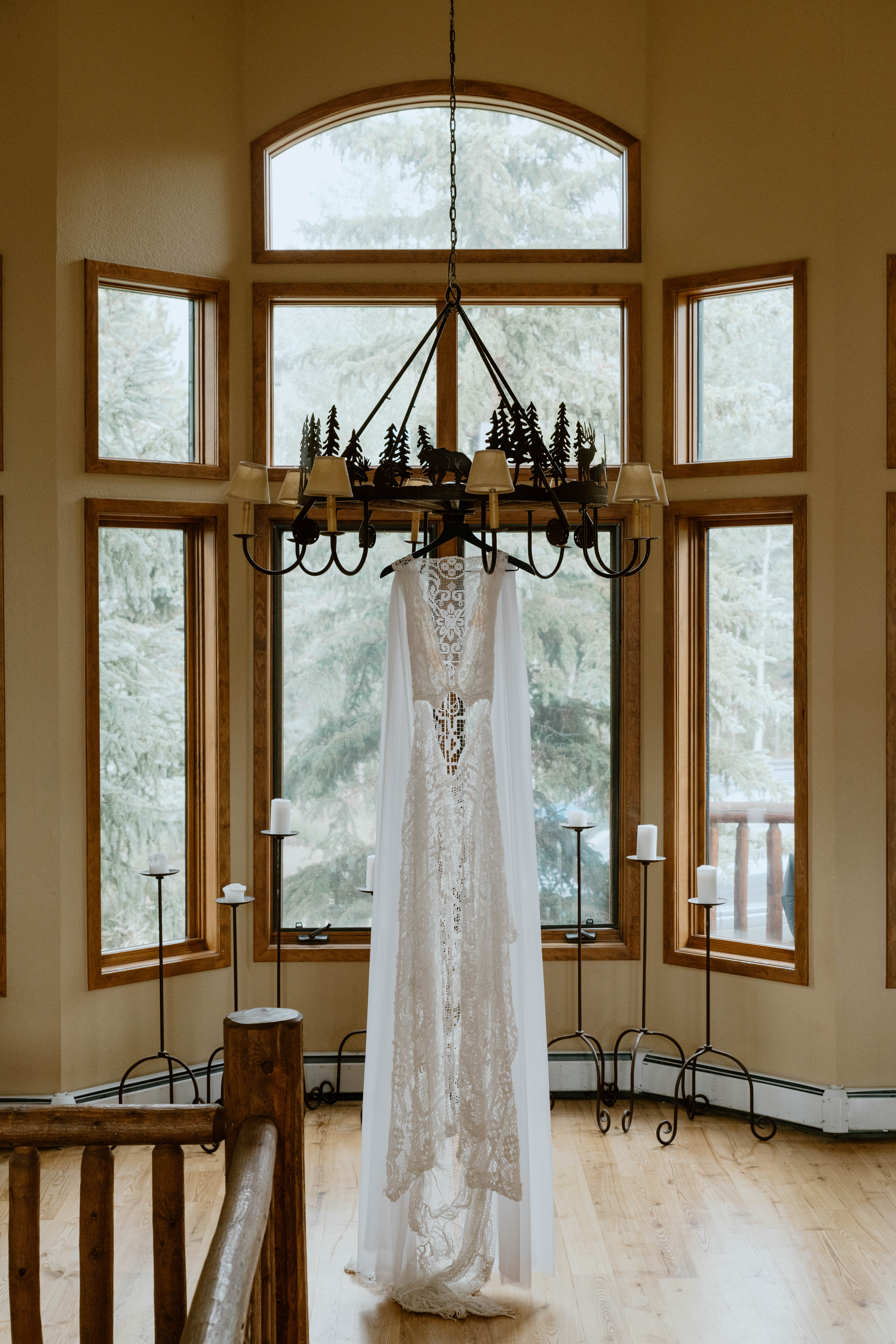 A wedding dress hangs from a rustic chandelier in a cabin in Colorado
