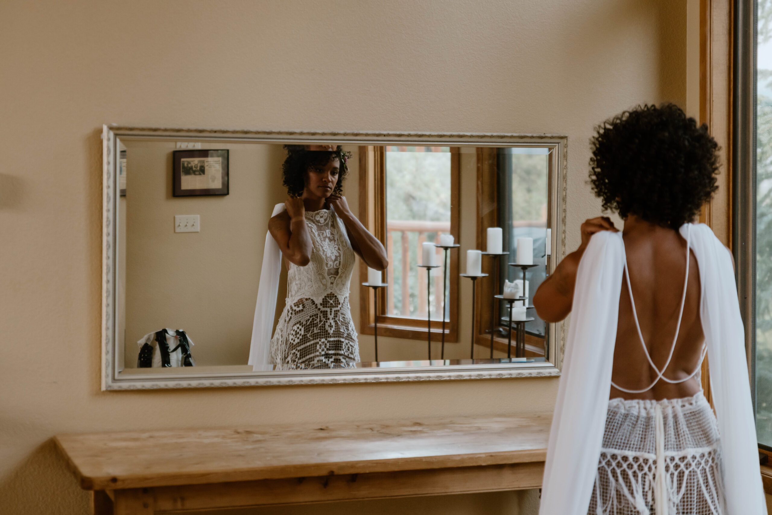 A woman stands looking in a mirror at herself in her wedding dress before the ceremony