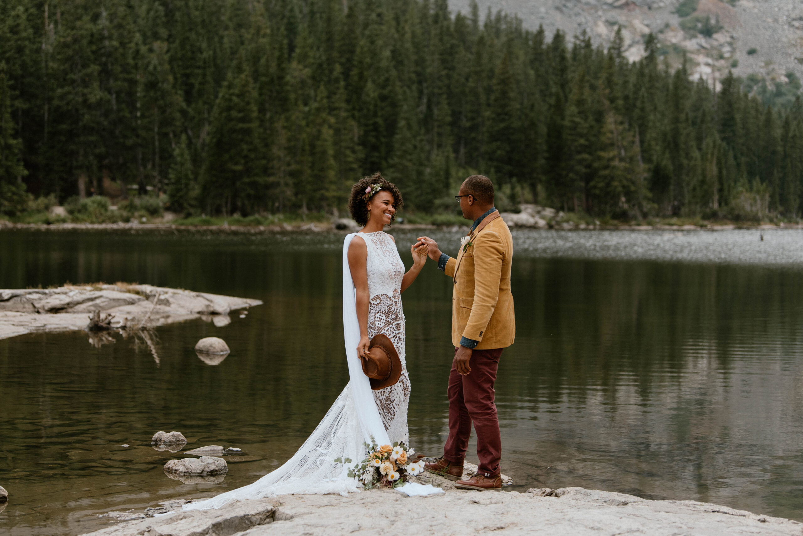 A husband and wife hold hands near a lake edge in Colorado