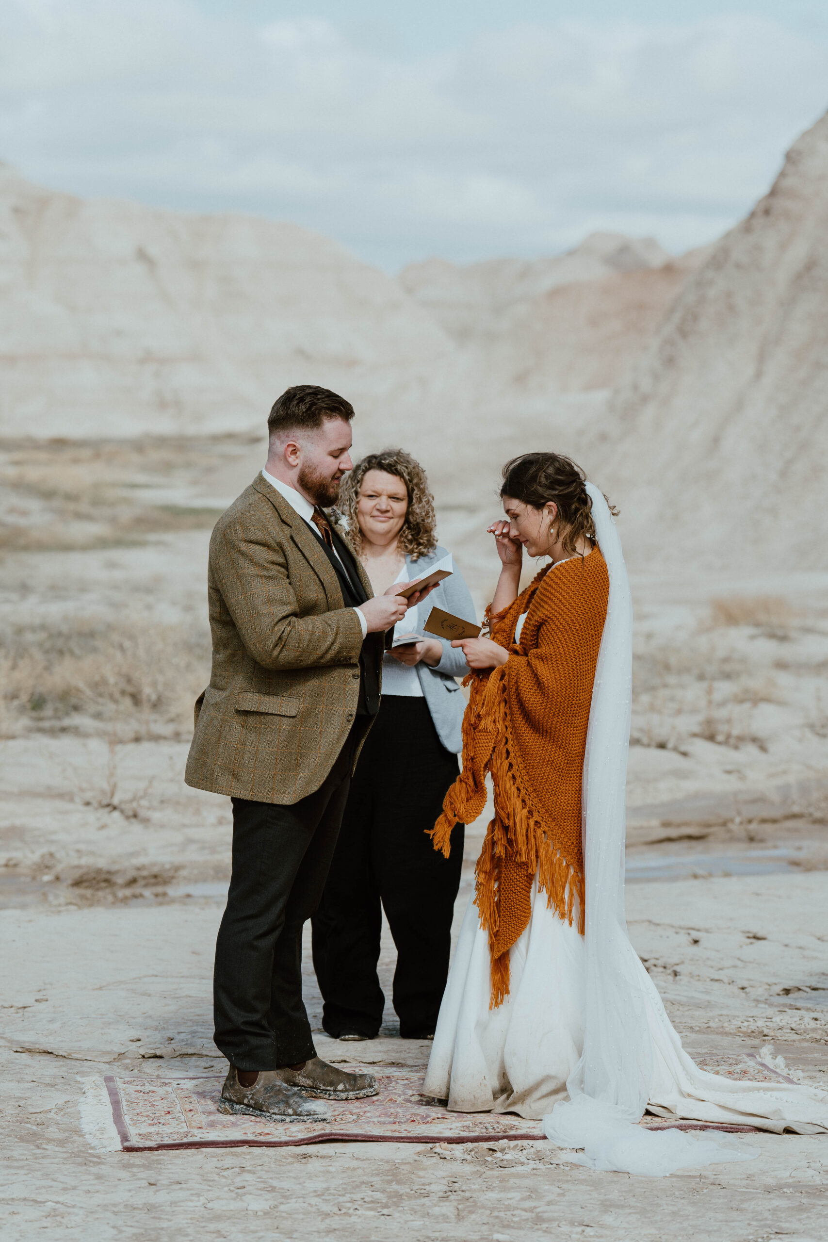 A couple reads their vows to one another in front of an officiant at their elopement in Badlands