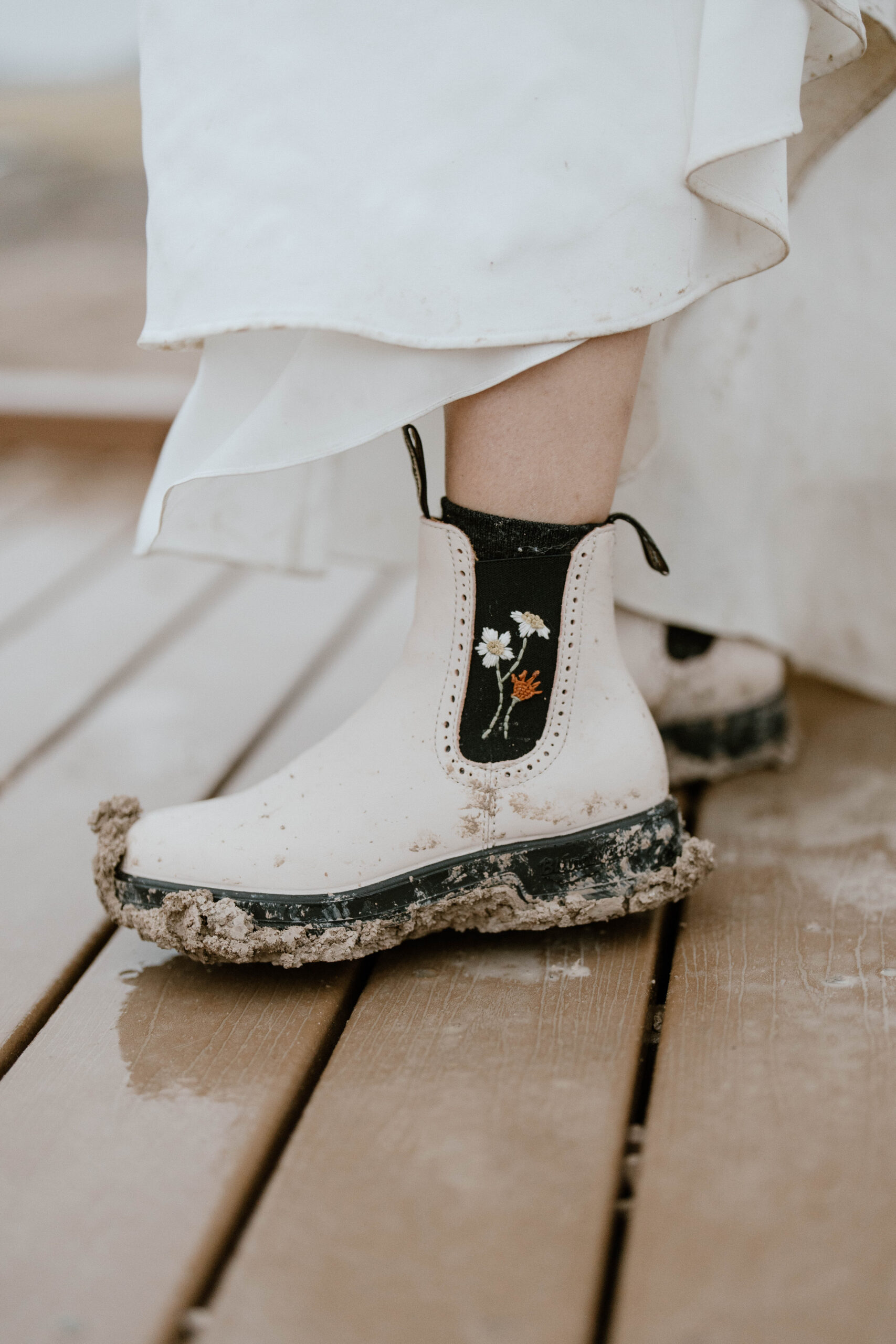 A pair of white women's Blundstones is pictured with embroidered flowers