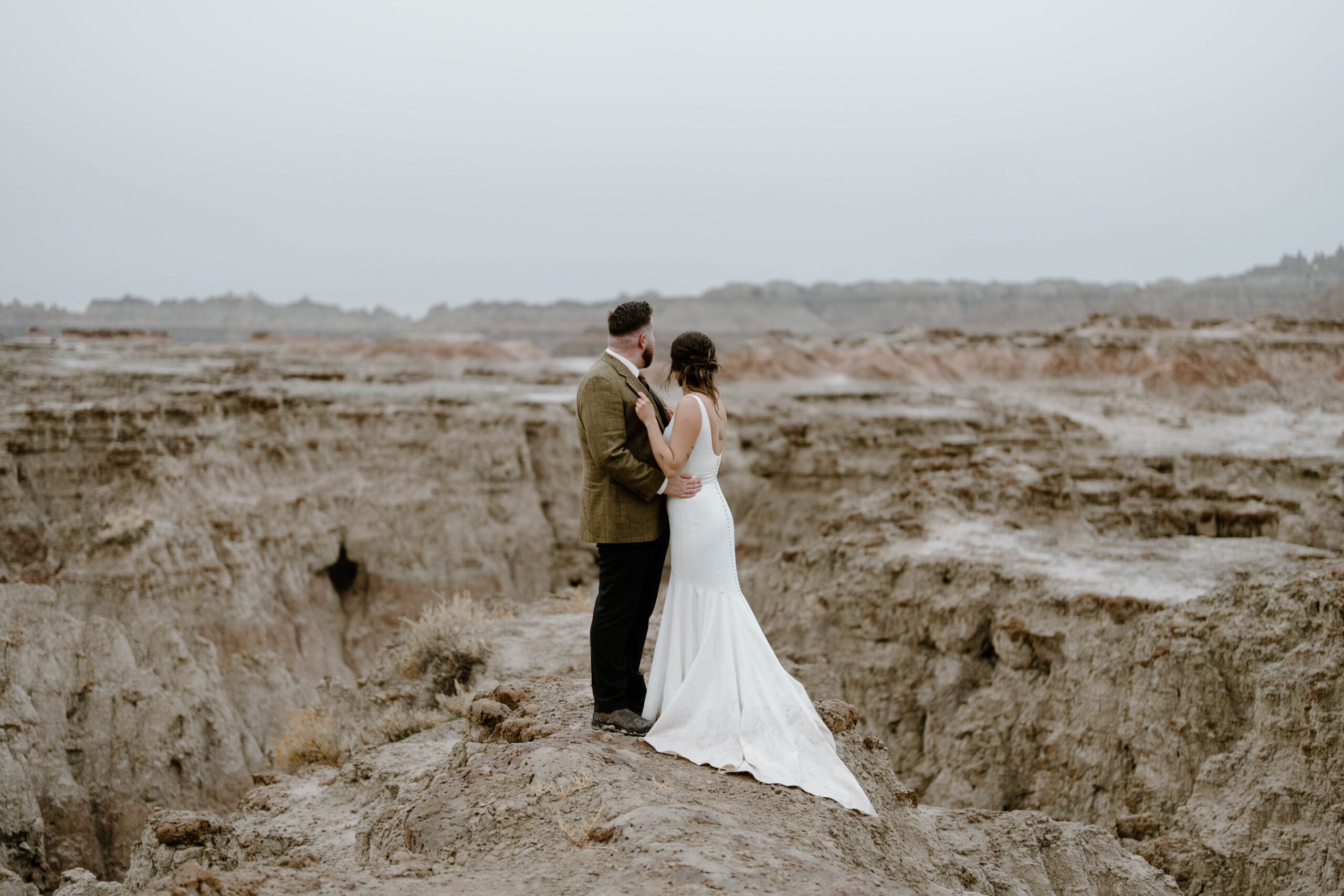 A couple is seen looking out onto a vast badlands landscape