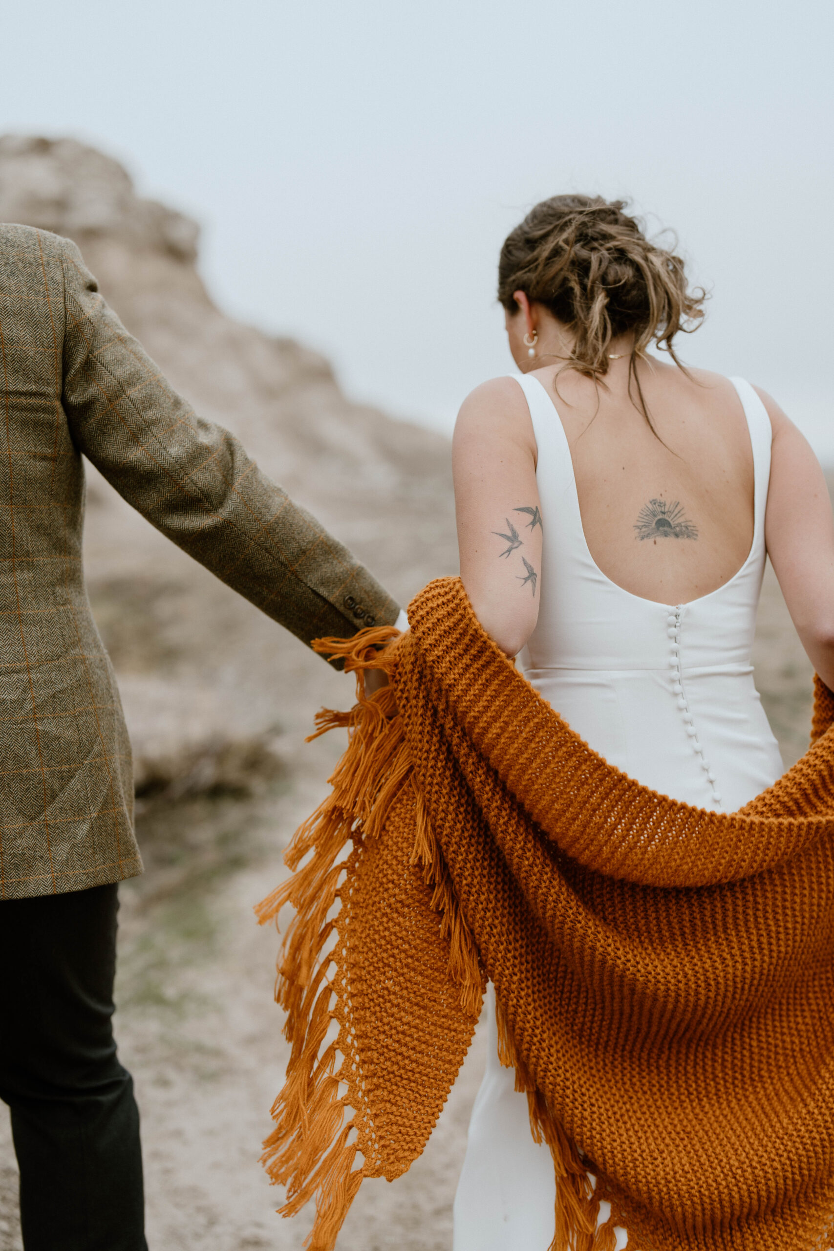 A bride follows her groom up to a picnic spot on their hiking elopement