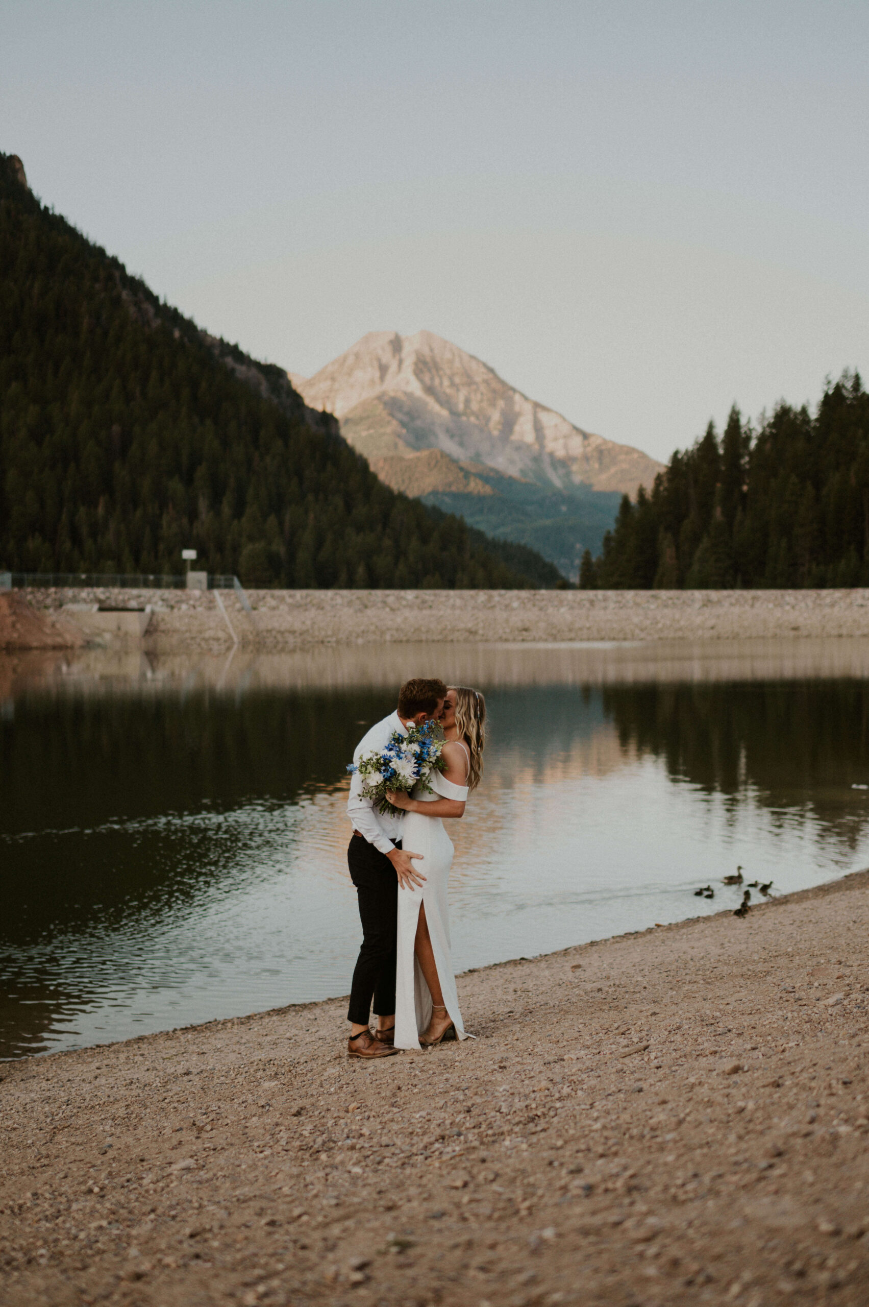 A couple elopes in Utah near a beautiful lake with a mountain in the background
