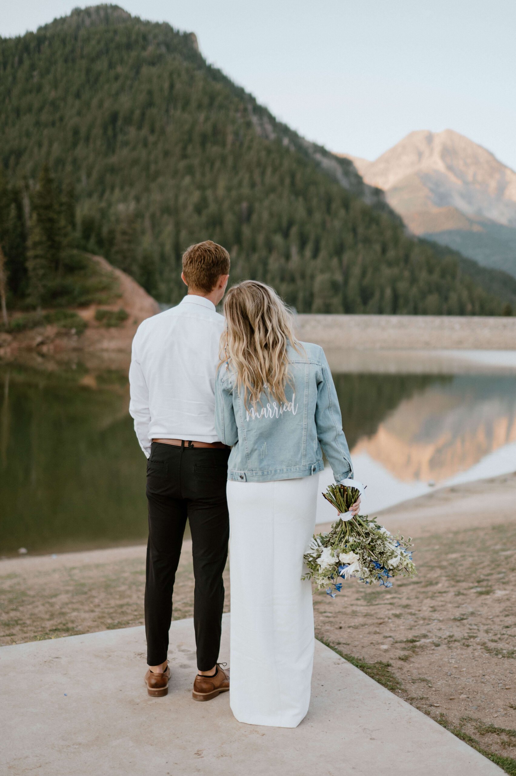A couple faces a beautiful lake and mountain range in Utah after saying vows