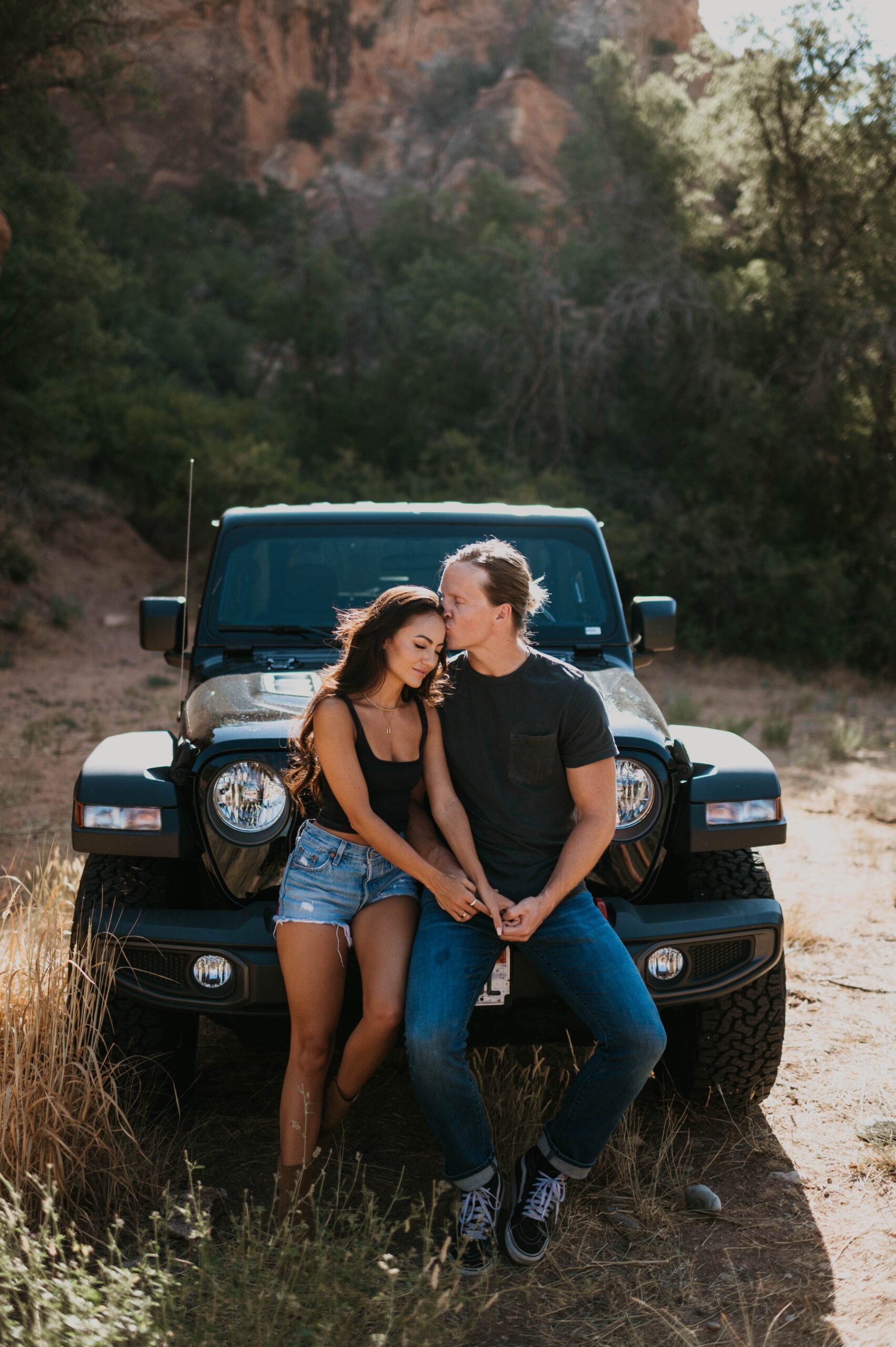 A couple leans against a 4x4 while celebrating their love in Utah