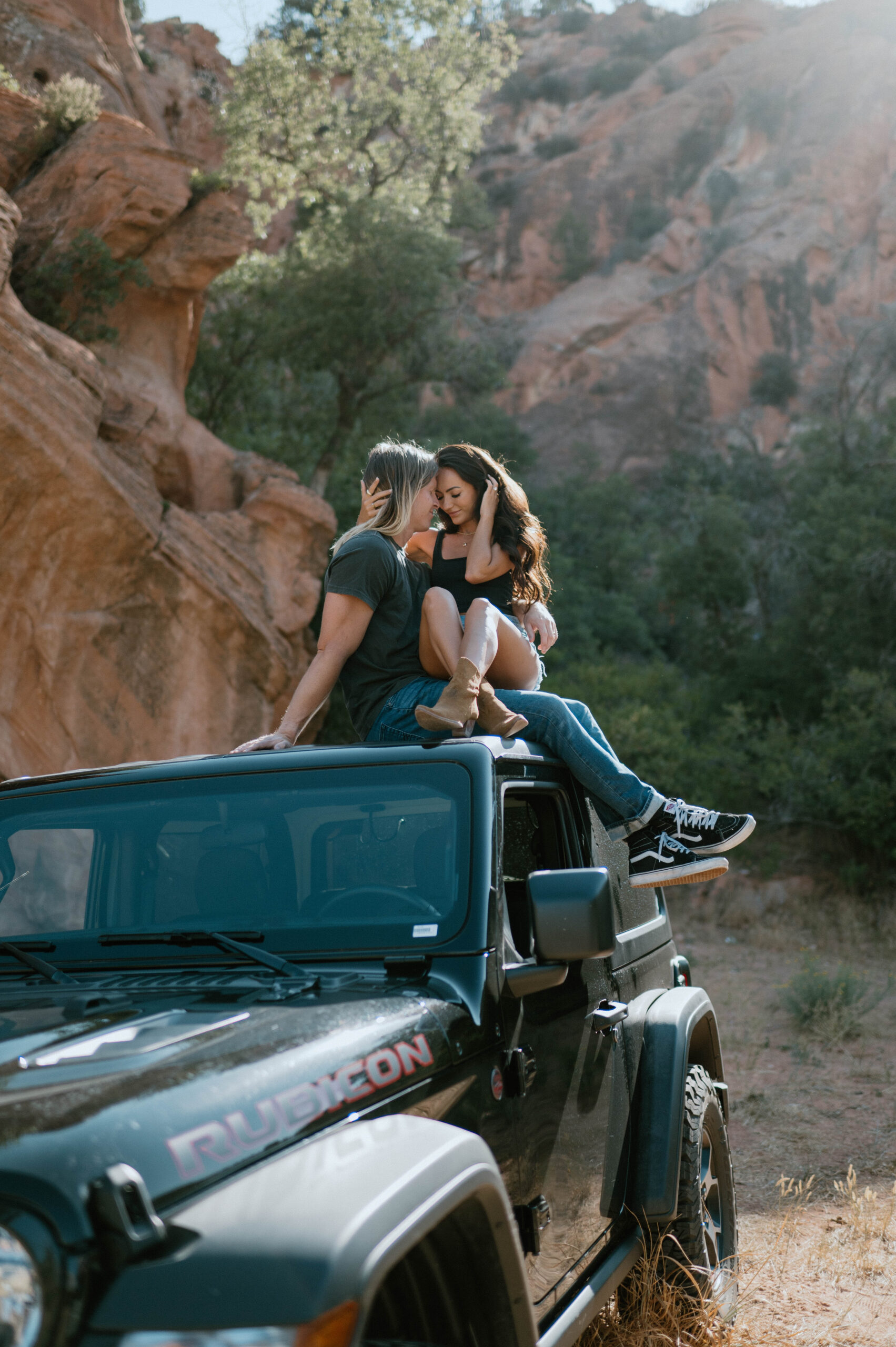A man and woman sit on the roof of a Jeep after off-roading in the red rock canyons of Utah