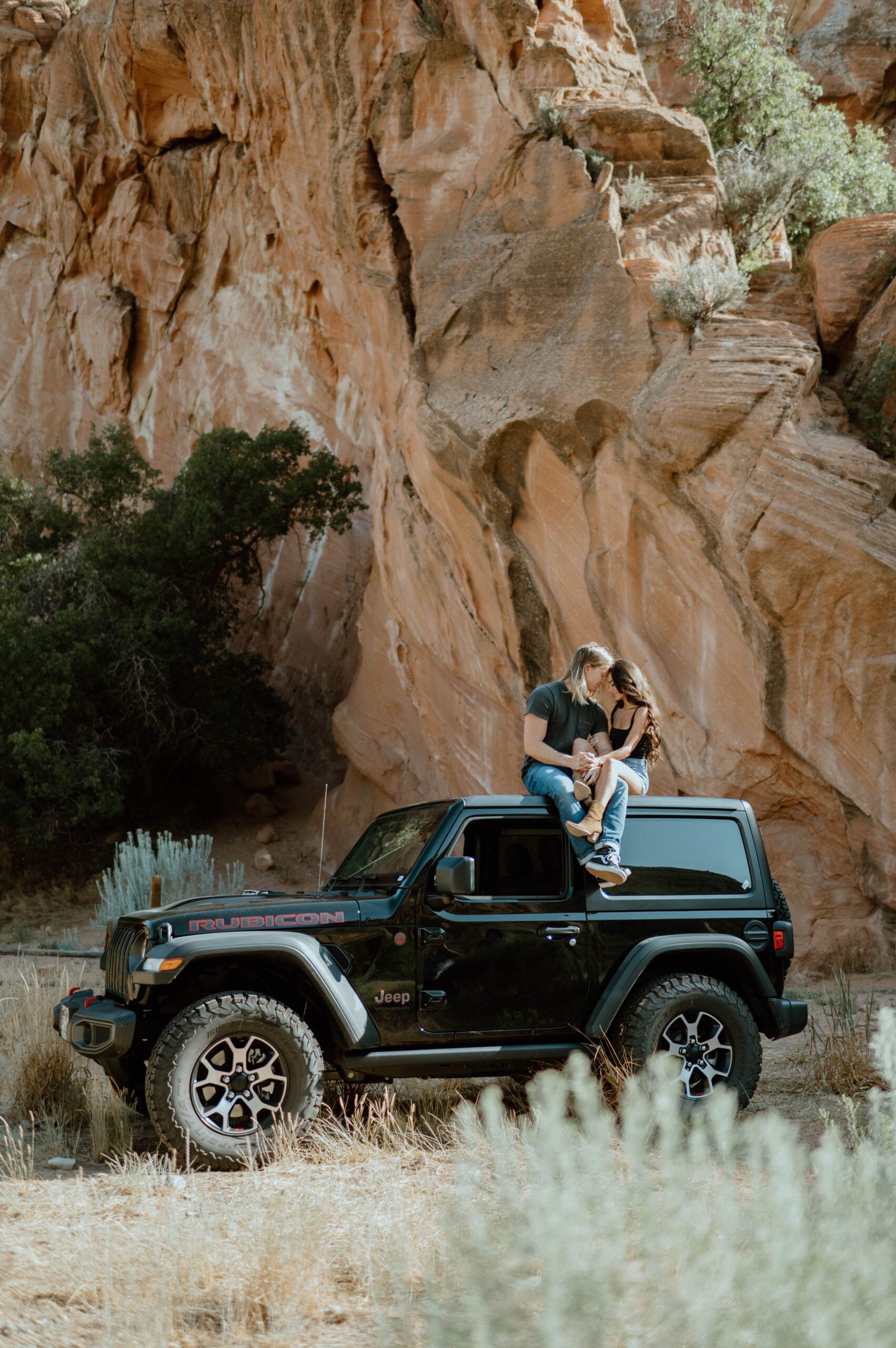 A couple sits on the roof of a Jeep on a break from off-roading in Utah