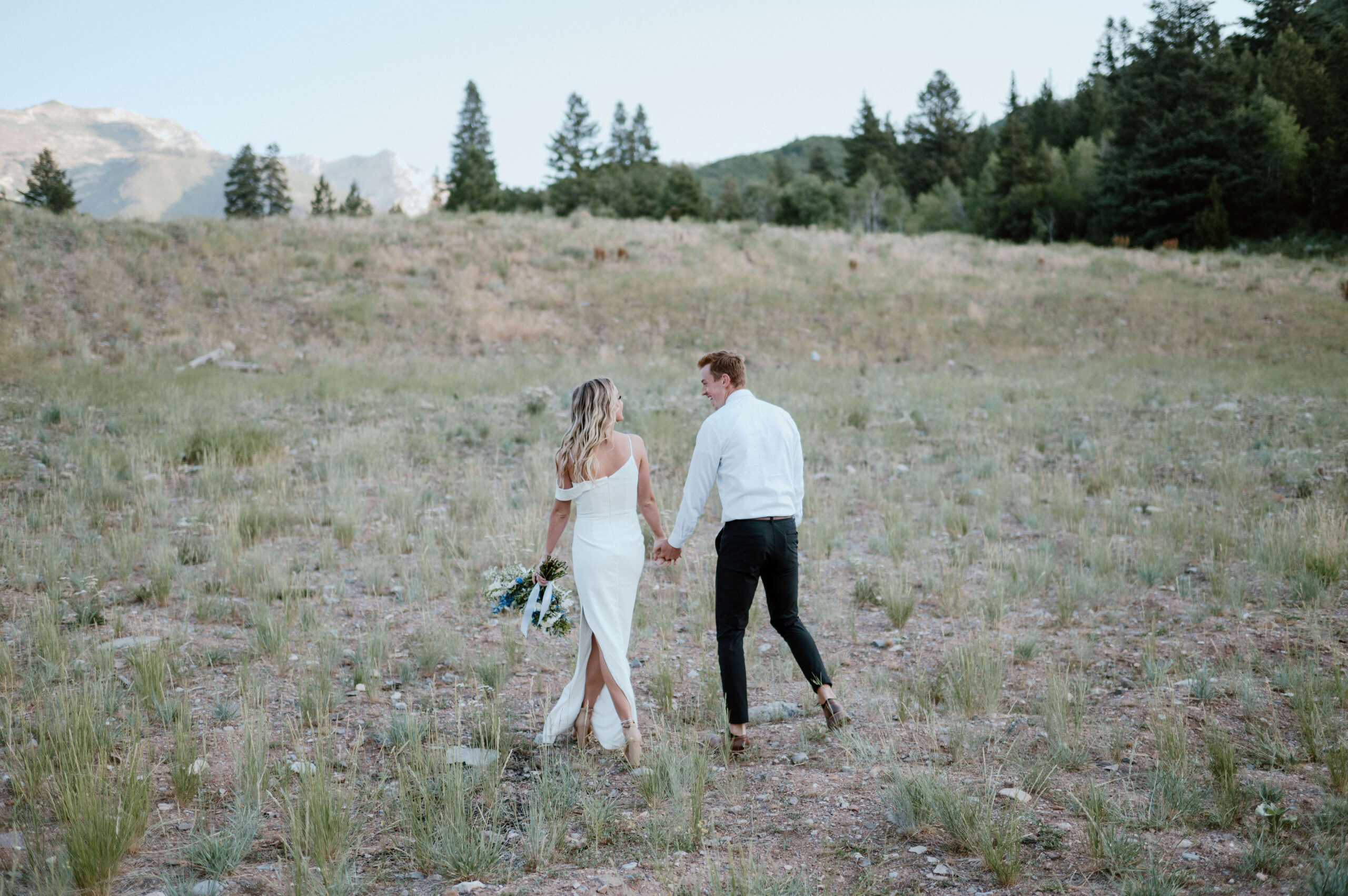 A couple walks in a meadow during their Utah adventure elopement