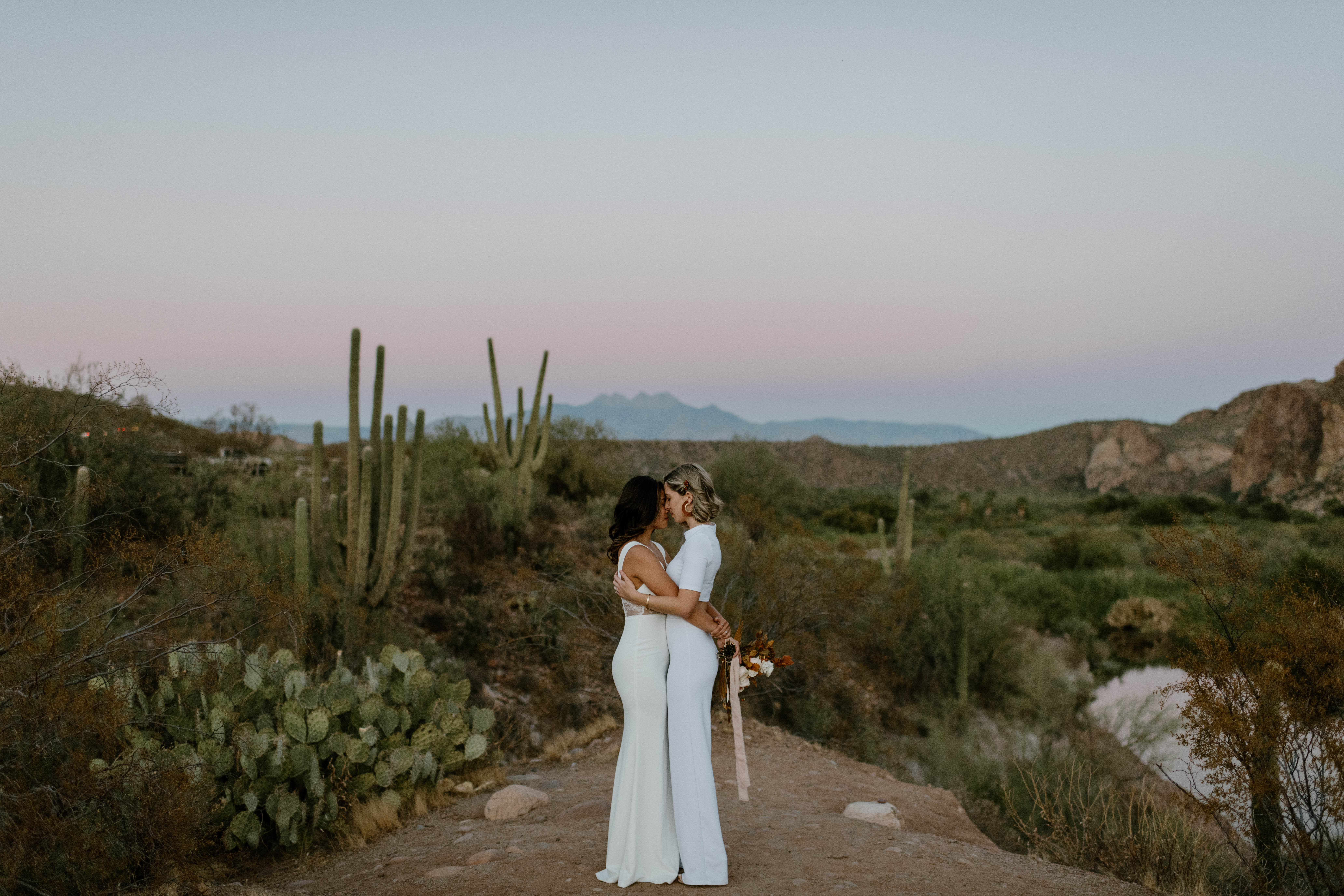 A couple kisses during an Arizona desert elopement in wedding attire at Sunset