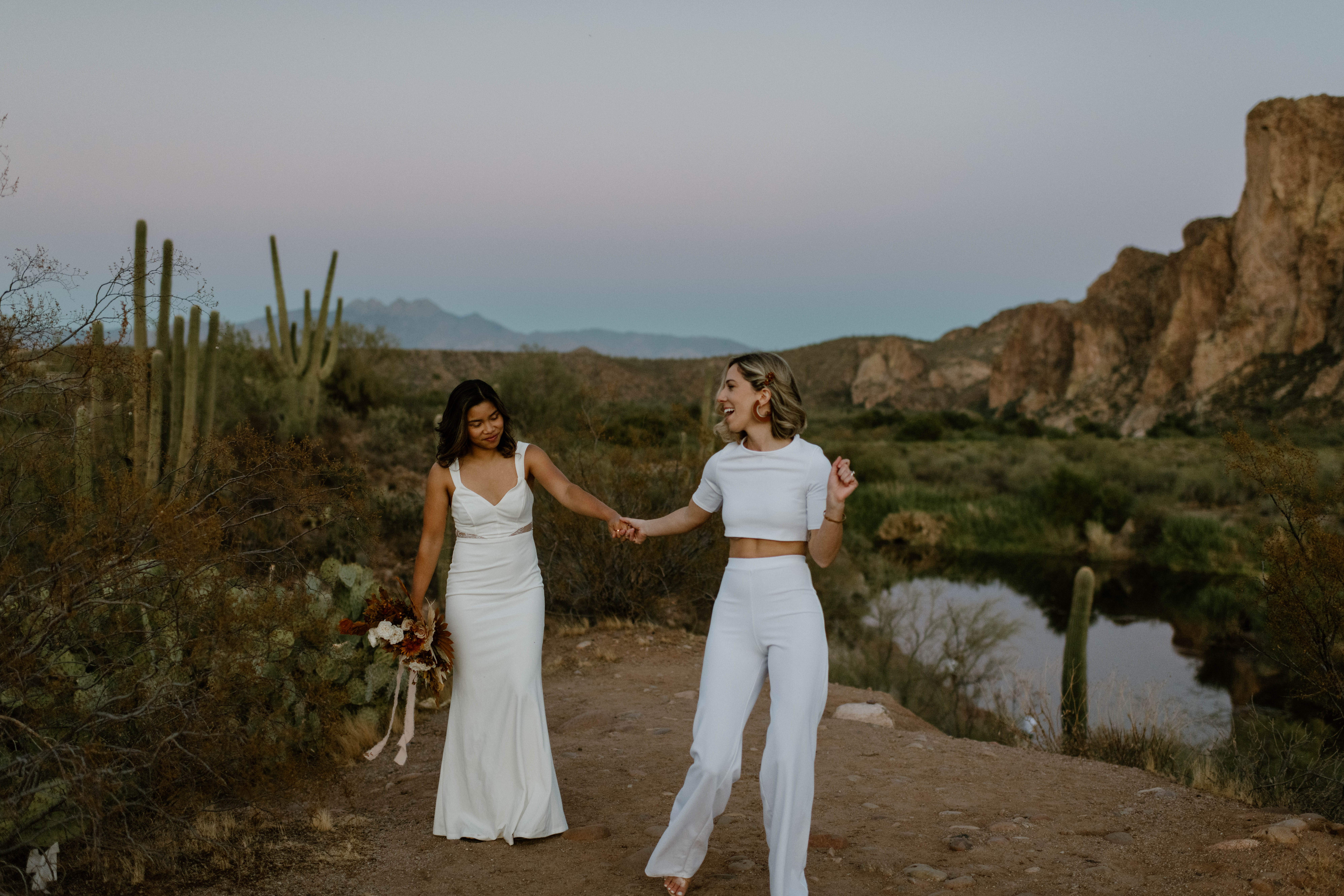 A woman leads her bride through the Arizona desert while celebrating their elopement
